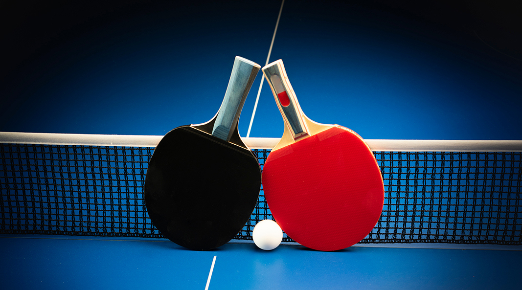 Ping pong rackets and ball on playing table.