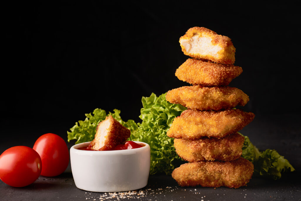 Stack of chicken nuggets with dipping sauce.