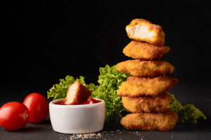 Stack of chicken nuggets with dipping sauce.