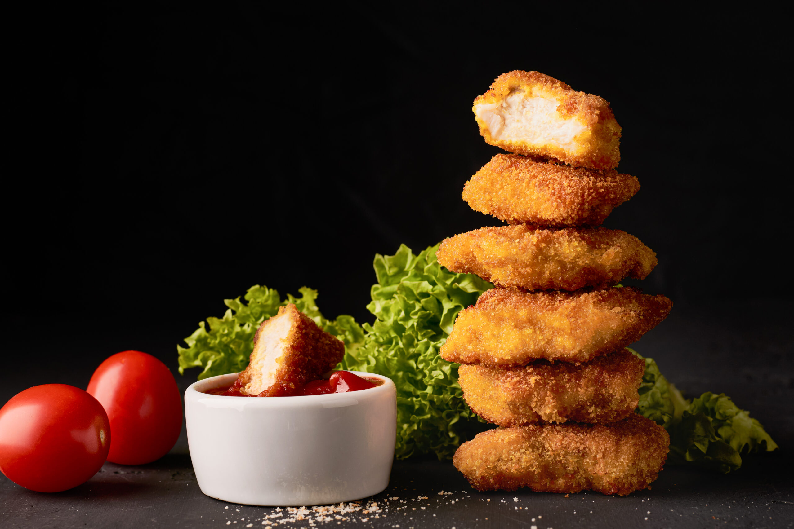 Stack of chicken nuggets with dipping sauce.