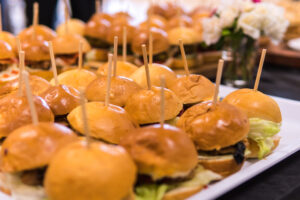 tray of small burgers on a table with black table cloth, National Hamburger Day.